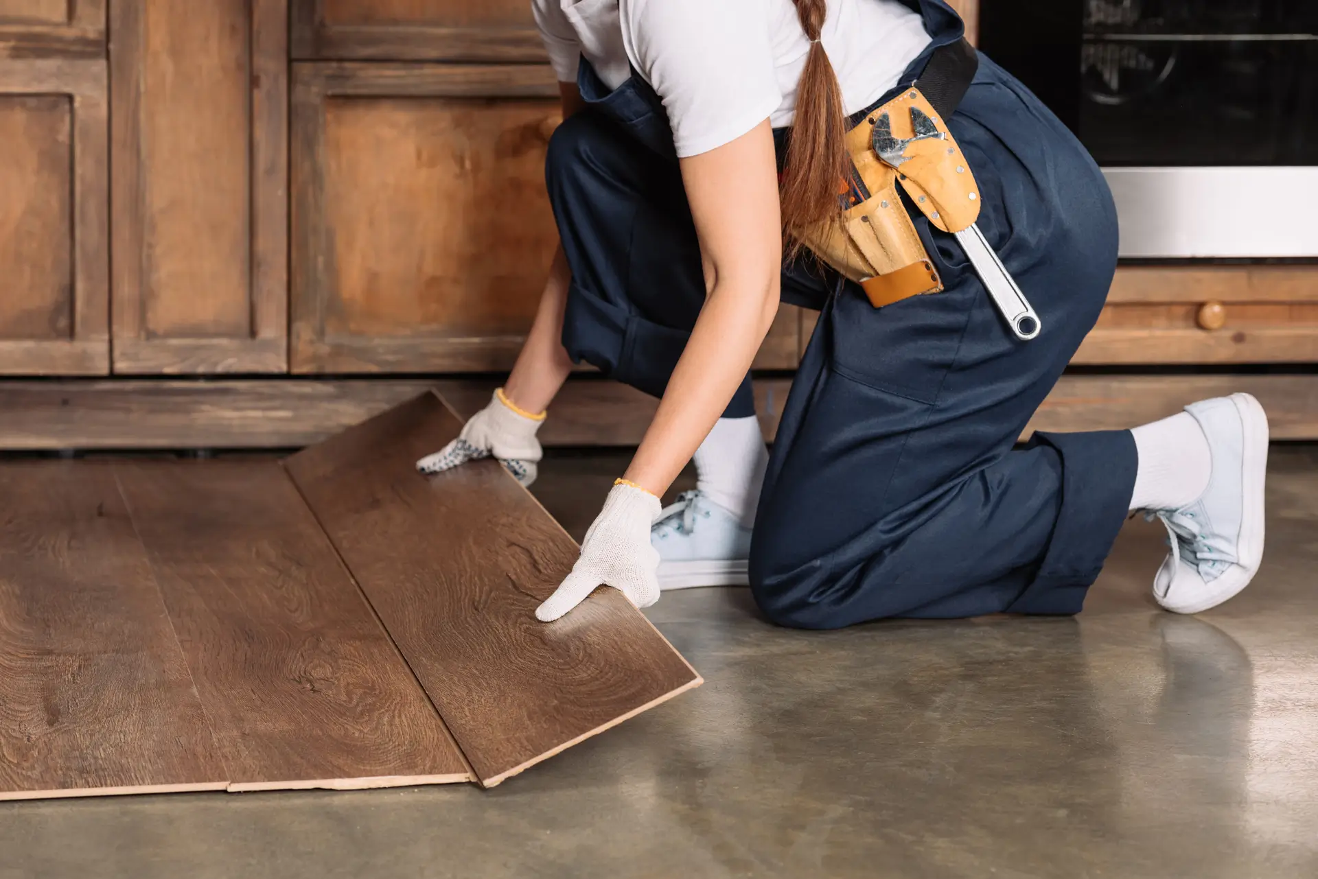 cropped shot of repairwoman installing laminate on floor